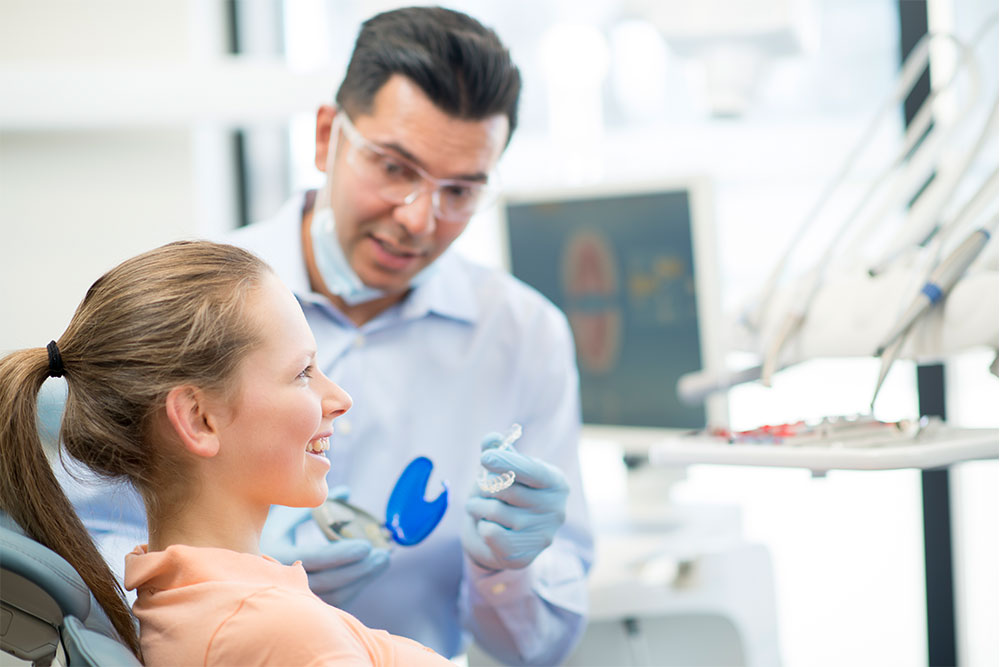 Orthodontist fitting dental retainer on patient
